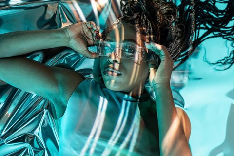 A young African woman embraces the metaverse wearing futuristic glasses. The image conveys