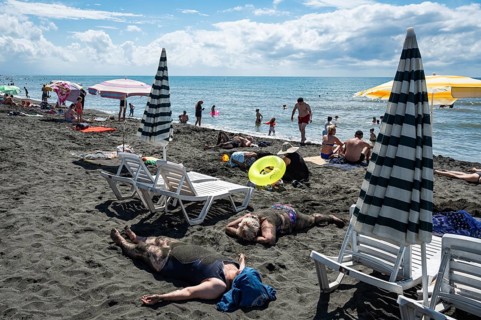 UREKI, GEORGIA - AUGUST 22, 2023: People on the beach with black sand