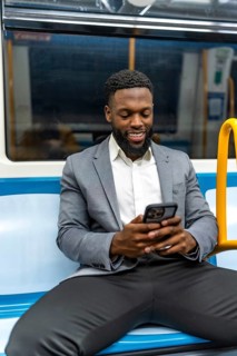 Smiling businessman using a mobile phone app while commuting on a subway train, enjoying the