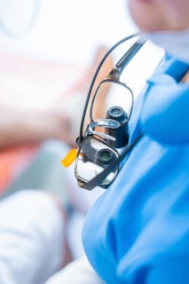 Close-up of medical magnifying glasses worn over a blue gown, dental practice, Germany