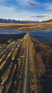 Vertical drone shot of a road stretching through the rugged Icelandic landscape near Hofsos, with