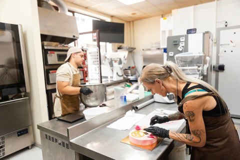 Two skilled pastry chefs work diligently in an Italian bakery, one mixing ingredients and another