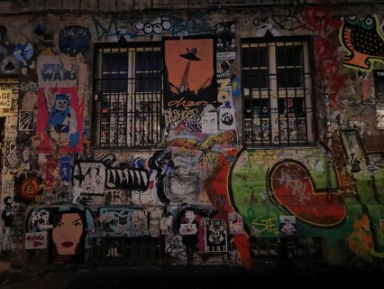 Colourful street art covers a wall with barred windows in an urban scene, Berlin