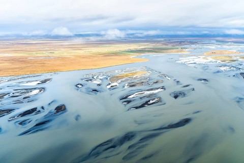 A stunning aerial shot capturing the dynamic rivers along Iceland's coast, showcasing swirling
