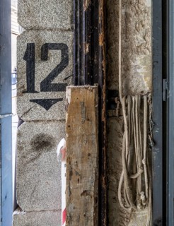 An industrial-themed image showing peeling paint on an old wall, rusty pipes, and coiled ropes. A