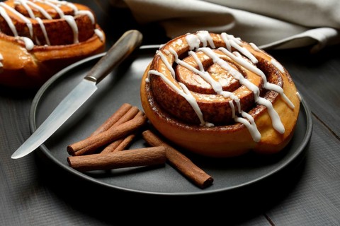 Cinnamon roll on plate and cinnamon sticks