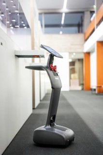 Modern robot with screen in a bright interior with carpeted floor, interactive guided tours by