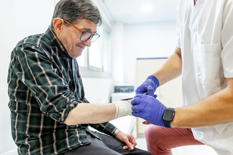 A healthcare professional wearing gloves cares for a patient in a mental health residence,