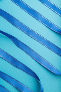 Blue ribbon on a blue pastel background. Celebration concept. Top view, close up, flat lay