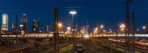 View over rails and moving train to the main station, in the background the colourful skyline of