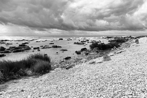 Characteristic coastline, wild natural beach, boulders, dramatic cloudy sky, monochrome, film set,