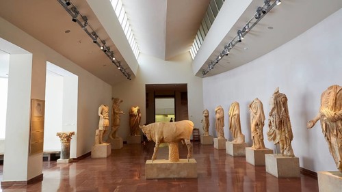 Classical Greek marble sculptures and the sculpture of a bull, interior of a museum with numerous