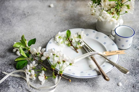 An elegant table setting features a white plate adorned with delicate blossoms and vintage cutlery.