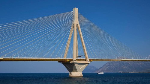 Suspension bridge with concrete pillars and a passing ship, Rio-Antirrio cable car bridge, Patras,