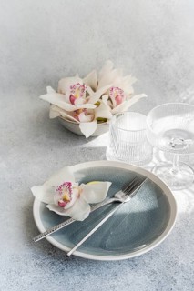 A sophisticated table setting features a blue plate with silver cutlery, adorned with delicate