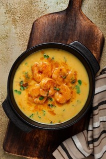 Creamy shrimp curry with spices, garnished with herbs, on a textured background, homemade, no
