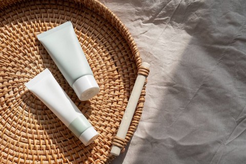Skincare cosmetics on a woven basket with soft natural light, capturing a minimalist aesthetic.