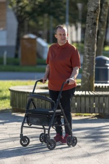 A man with an intellectual disability uses a mobility walker while strolling through a park. His