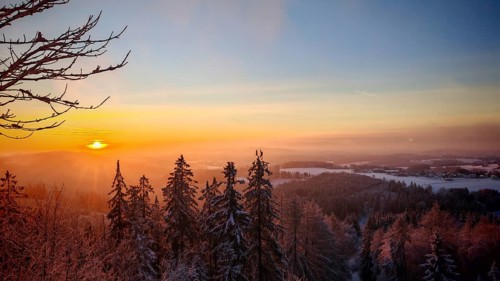 View from Döbra Berg, wide winter landscape with spectacular orange sunset with snow and trees,