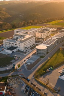 Aerial view of a modern building complex with surrounding fields at sunset, new hospital at the