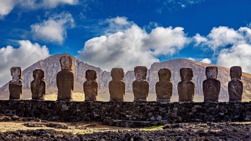 Moai statues against a mountain backdrop and dramatic sky with clouds, The Moai statues on Easter