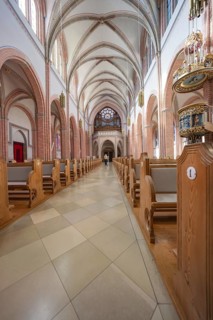 Long church corridor with high vaults and glass windows, wooden benches left and right, Sacred
