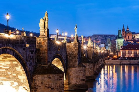 Breathtaking view of the Charles Bridge in Prague, featuring statues and city lights reflecting on