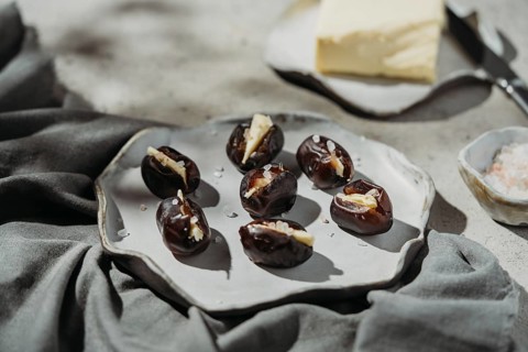 A plate of dates filled with creamy butter and sprinkled with sea salt. The rustic ceramic setting