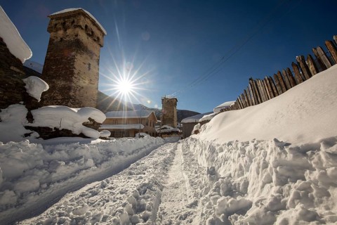A picturesque winter scene of a snow-covered village with ancient stone towers in Georgia The