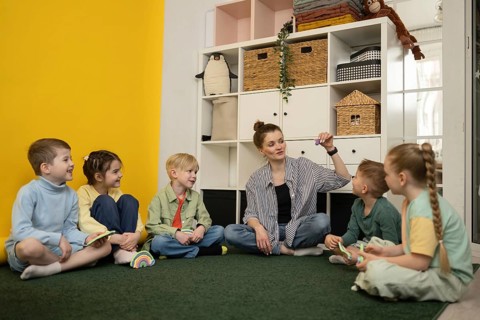 A group of young children attentively participate in an interactive lesson led by a teacher in a