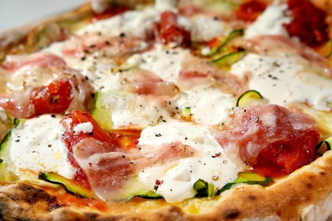 Detail shot of a delicious gourmet pizza with fresh toppings, including mozzarella, prosciutto,