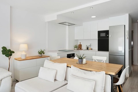 A minimalist kitchen and living space featuring a sleek white design in the city center. The wooden