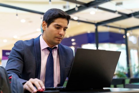 A young Chilean businessman intently working on his laptop in a modern office setting, showcasing