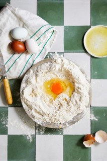 Top view of a homemade pastry preparation with eggs, flour, and a bowl of whisked mixture on a