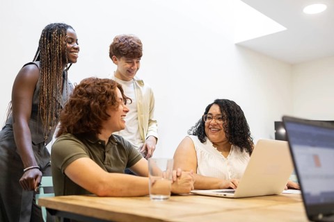 A diverse group of colleagues collaborate in a modern office setting. They are engaged in a