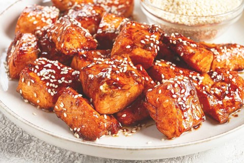 Fried pieces of salmon teriyaki with sesame seeds, top view