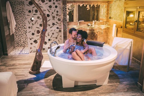 Happy interracial couple relaxed in the jacuzzi enjoying their self and drinking wine