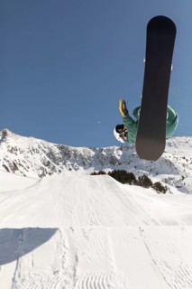 A snowboarder executes a thrilling aerial trick against a stunning mountainous backdrop, showcasing