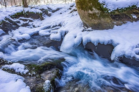 Small watercourse in winter with ice floes and mossy stones, Brühlbach below Urach Waterfall, Bad