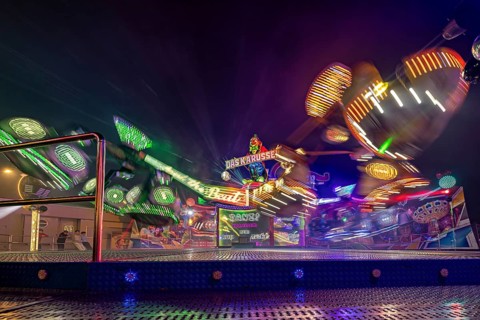 A carousel at a fair at night, surrounded by colorful light shows in fast motion, carousel and the