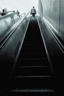 A man climbs a long, modern escalator in monochrome colours, Schlossplatz, Stuttgart, Germany