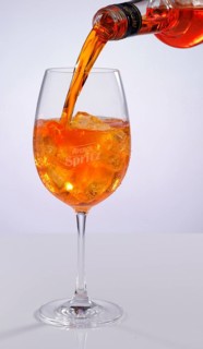 Aperol is poured into an Aperol spritz glass on ice cube cubes, studio shot