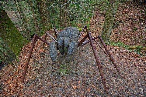 Large spider figure in the forest, wood sculpture, wood carving, chainsaw art, modern art,