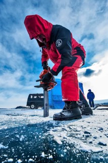 Digging a hole in ice for scuba divers with a chainsaw, Lake Baikal, Olkhon Island, Pribaikalsky
