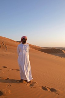 Bedouin man in white dishdasha on a sand dune, Wahiba Sands or Rimal Al Wahiba or Sharqiyya Sands