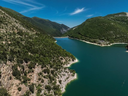 A captivating aerial view of Lago di Fiastra in Italy, surrounded by lush green hills and clear