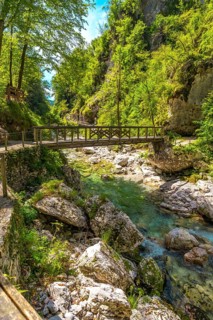 Scenic wooden footbridge crossing crystal clear turquoise waters of tolmin gorge, surrounded by