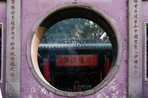A serene view through a circular stone gateway at a Taoist and Chinese Buddhist temple in Macau,