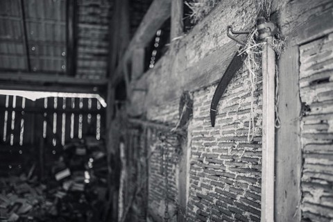 A scythe hanging on the wall of an old barn in Poland