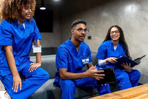 Group of diverse healthcare professionals in blue scrubs talking and sharing information while